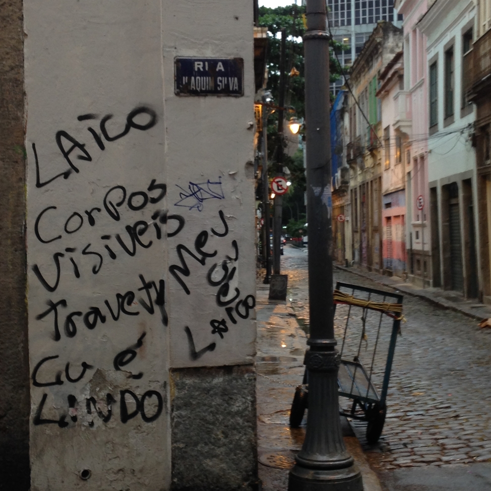 Pichações na rua Joaquim e Silva, próximo ao número onde Madame Satã morou, com a Casa Nem pintada nas cores da bandeira trans ao fundo (Foto: João Ker | Revista Híbrida)
