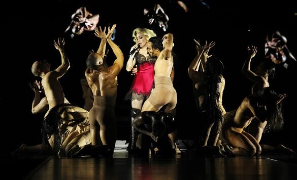 Madonna de camisola vermelha cercada por dançarinos em show da turnê Celebration ( Kevin Mazur | WireImage for Live Nation)